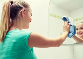Maid cleaning mirror